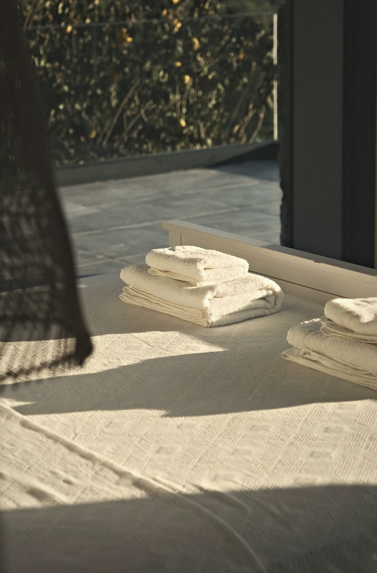 Afternoon sun across a white bedspread and folded towels