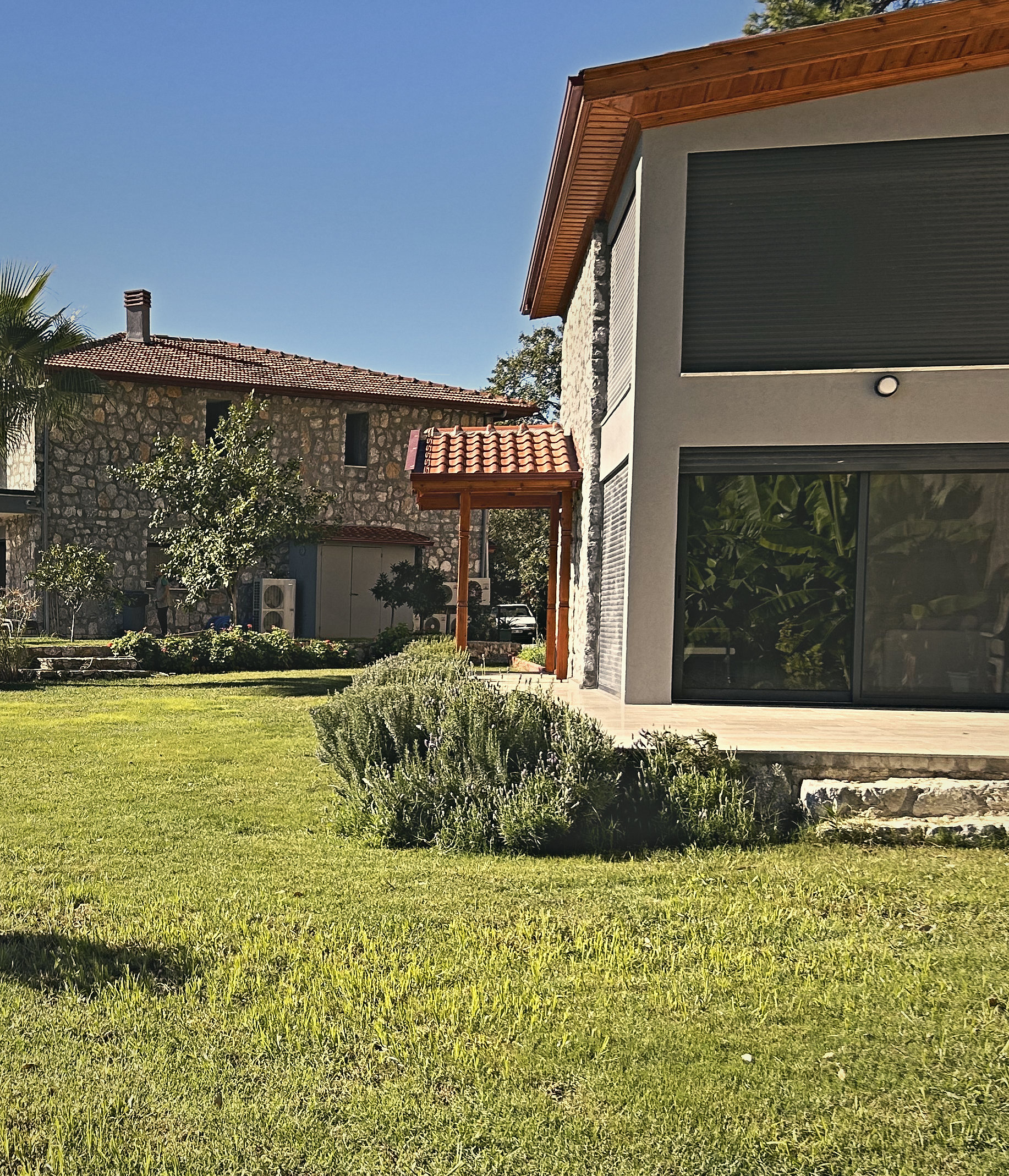 The Loft's tall glass doors and stone wall, with the main house beyond