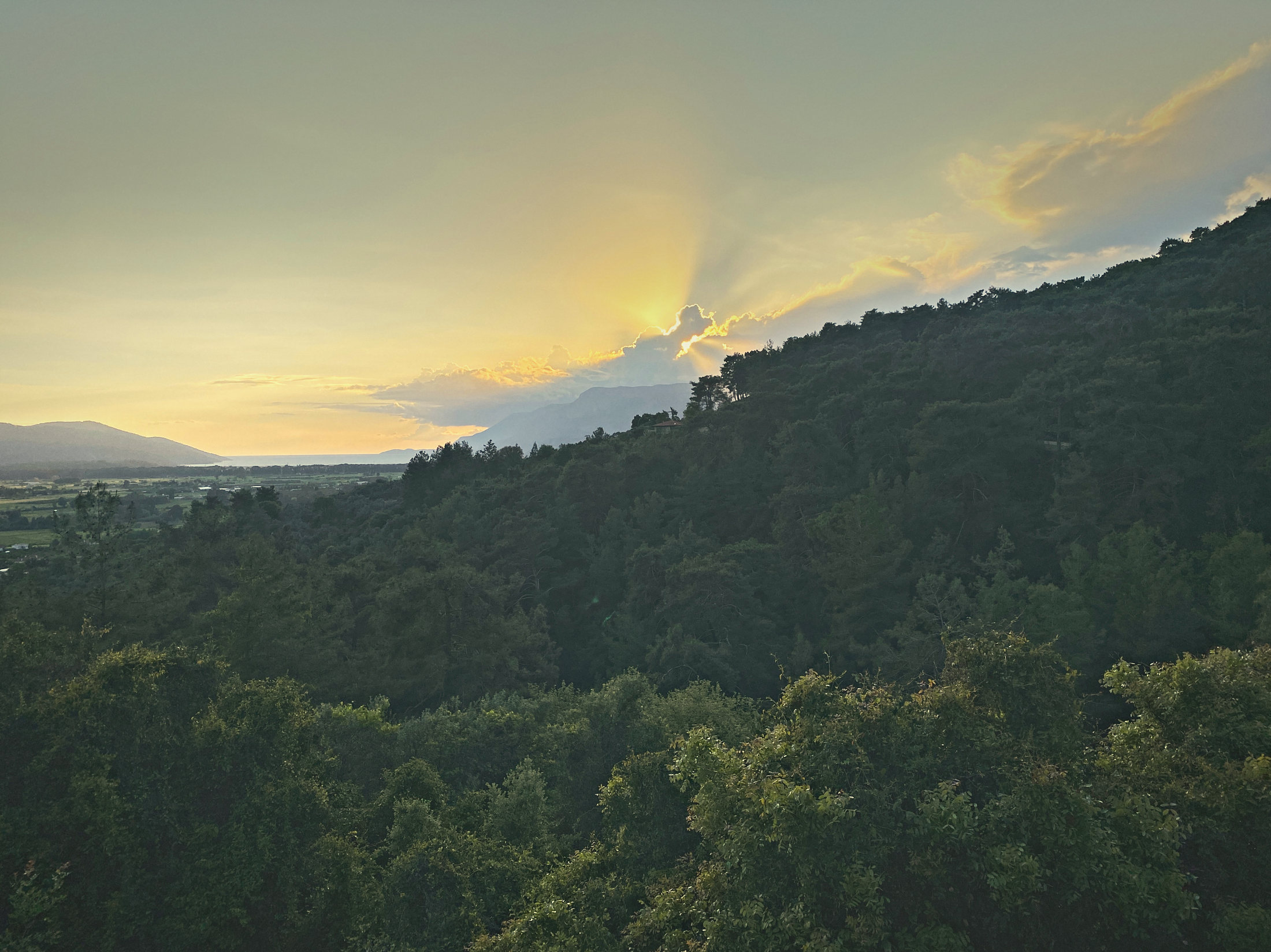 Sun breaking through cloud over the pine hills and the Gulf of Gökova